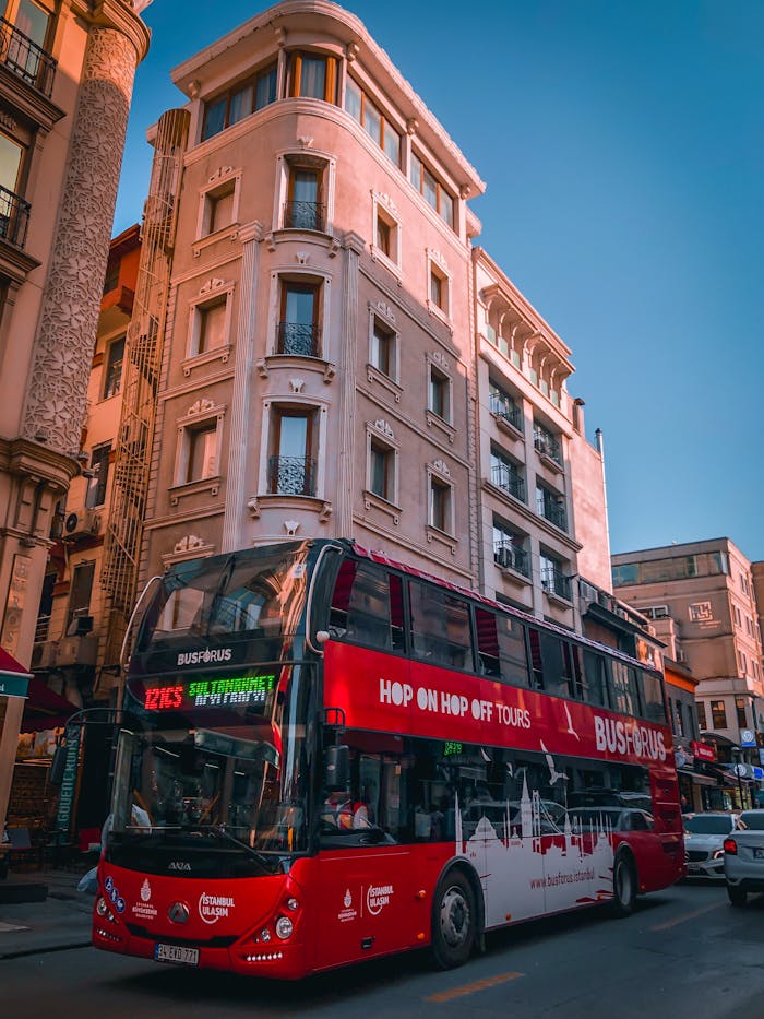 gallery-5 Red double decker bus touring a busy street surrounded by historic buildings.