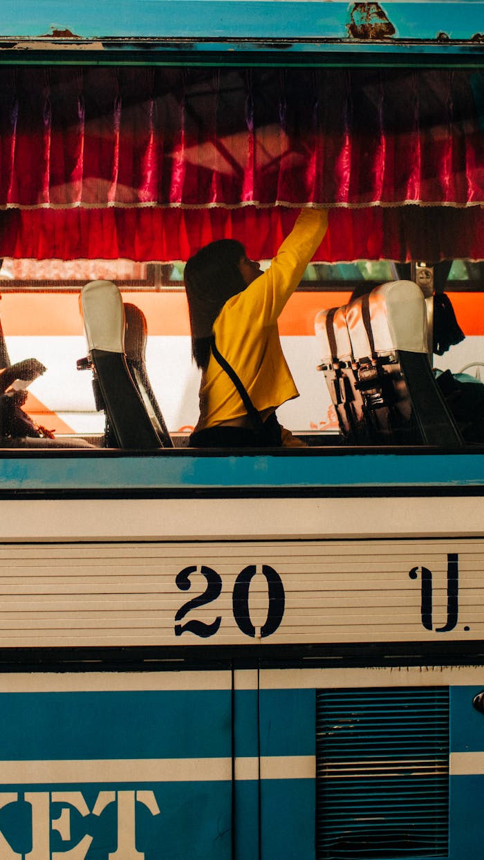 services-img A woman adjusting a curtain inside a vintage public bus during the day.