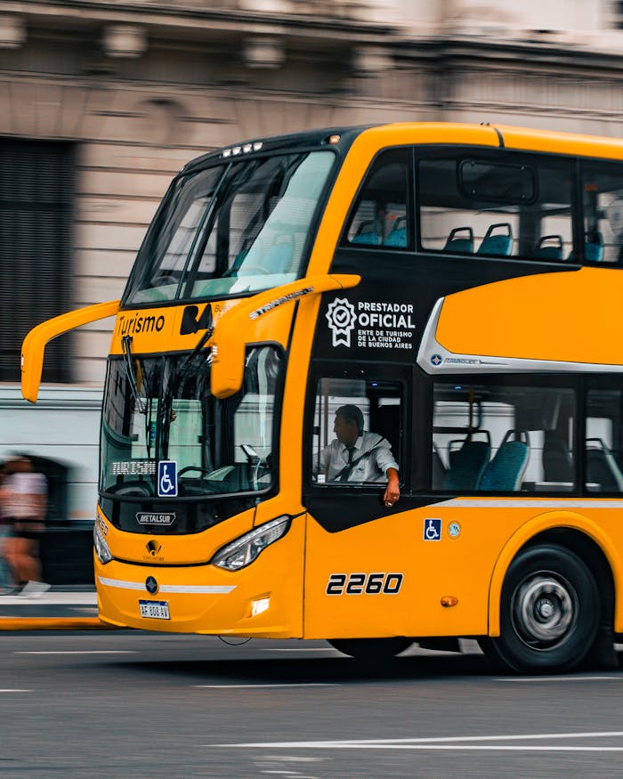 services-01 A yellow double-decker tour bus with official markings, driving in Buenos Aires city.